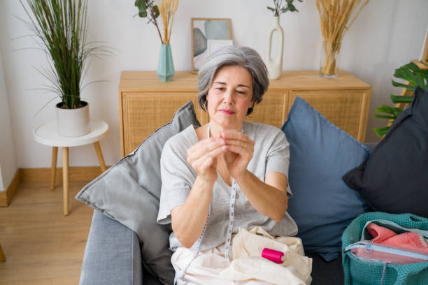 istock Senior designer woman sewing clothes at home on sofa 2159352131