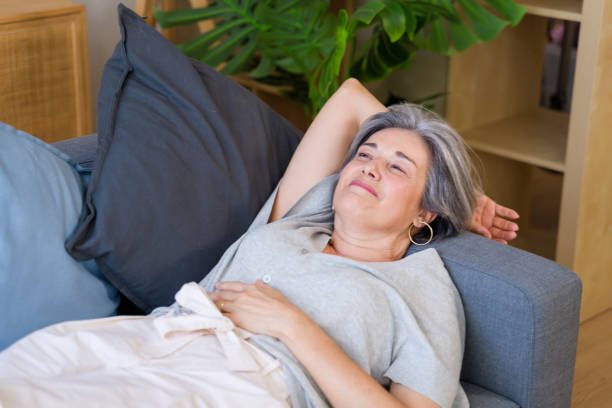 istock Senior woman relaxing on sofa at home enjoying retirement 2159352280
