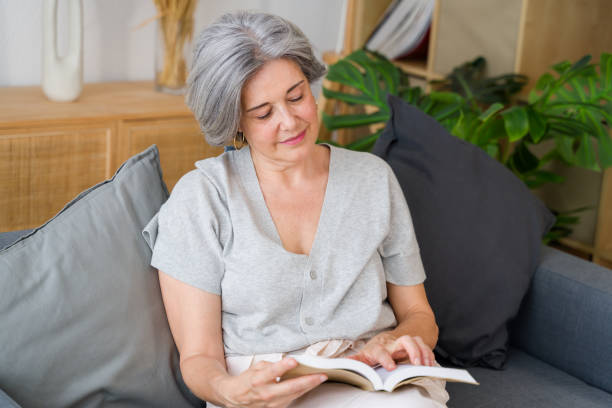 istock senior woman reading a book at home on the sofa 2159352285