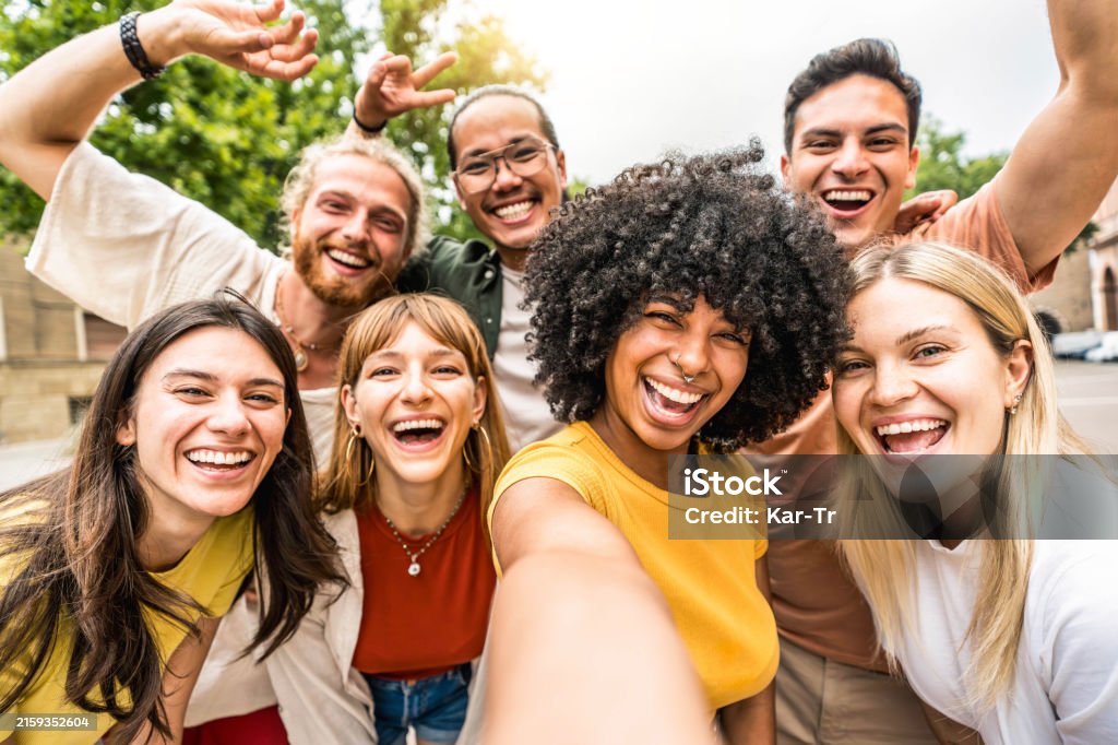 Des amis multiculturels souriant à la caméra ensemble à l’extérieur - Des jeunes heureux prenant un selfie avec un téléphone portable intelligent marchant dans la rue de la ville - Communauté de jeunes et concept technologique - Photo de Personne humaine libre de droits Des amis multiculturels souriant à la caméra ensemble à l’extérieur - Des jeunes heureux prenant un selfie avec un téléphone portable intelligent marchant dans la rue de la ville - Communauté de jeunes et concept technologique - Photo de Personne humaine libre de droits