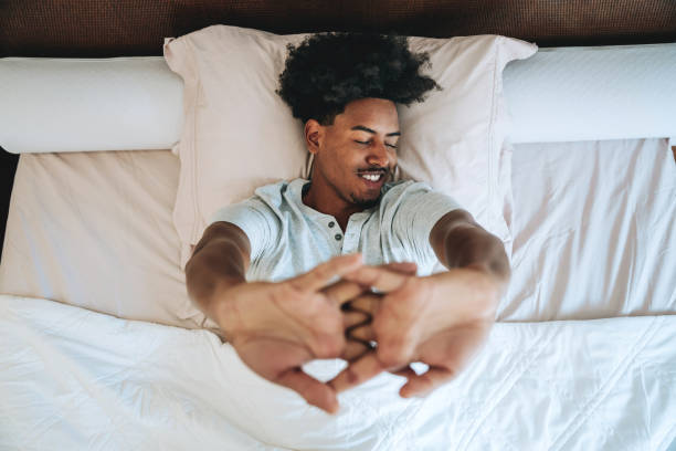 A young man waking up in his bedroom bed