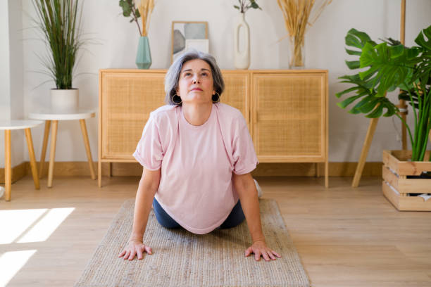 istock Senior woman doing yoga stretching exercise at home 2159353180