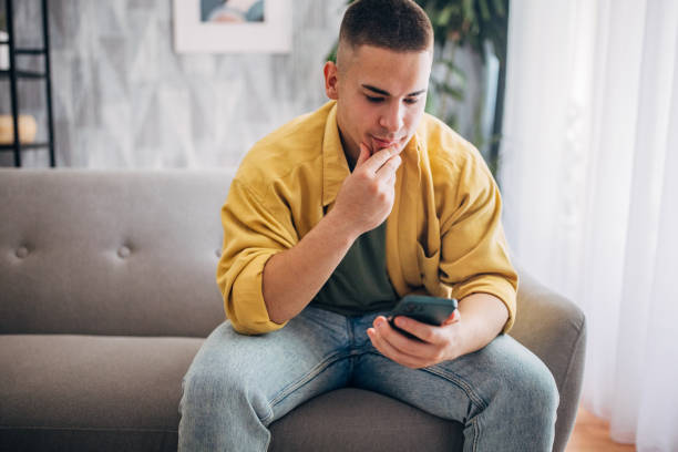 istock Contemplative man with smartphone at home 2159354878