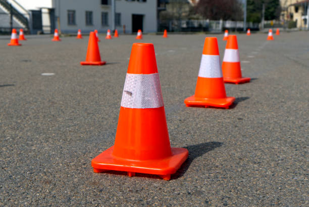 istock bright orange traffic cones standing in a row on dark asphalt 2159356324