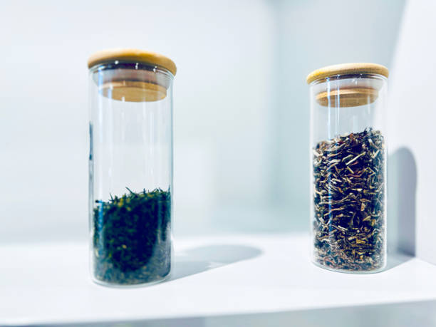 Two glass jars filled with dried herbs, displayed on a white surface