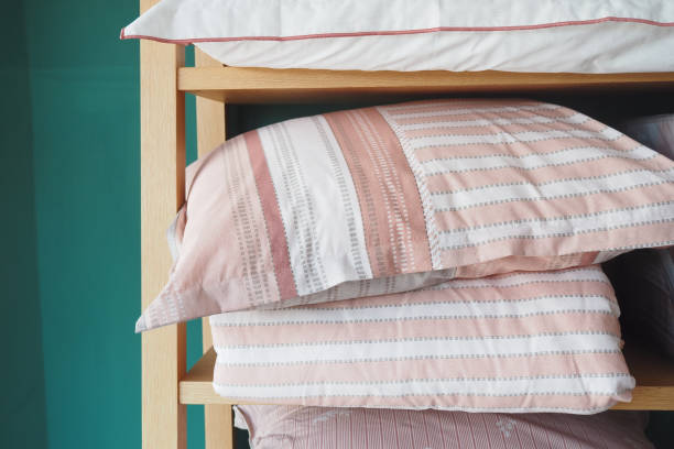 istock Several comfortable pink and white striped pillows neatly arranged on a wooden shelf in a bedroom 2159358665
