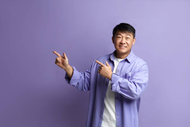 istock Smiling Man Pointing Hand. Positive Guy Pointing Away Paying Your Attention 2159365950