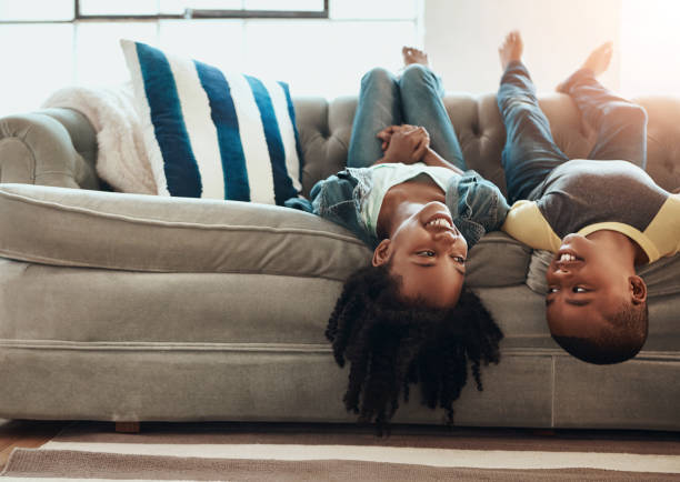 istock Upside down, relax and kids on couch, happiness and playing indoors for imagination, weekend break and siblings bonding together in living room. Children, home and boy with girl, fun and cheerful 2159367430