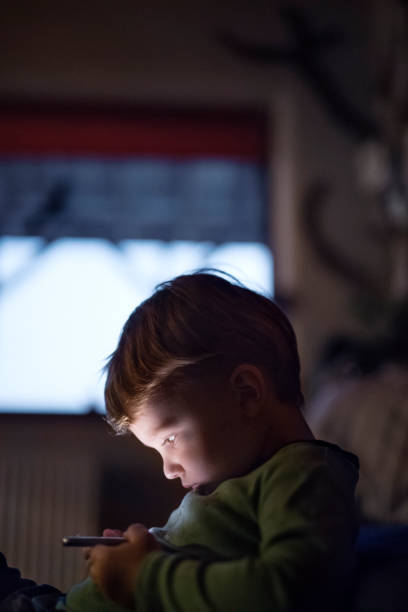 istock Cute boy sitting on bed watching something on smartphone. Children's screen time. 2159367616
