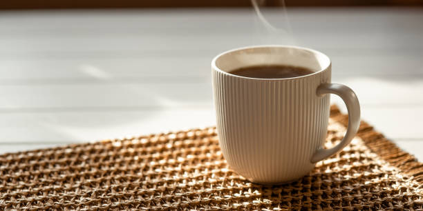 istock A steaming cup with a hot drink in the sunlight on the table. 2159367770