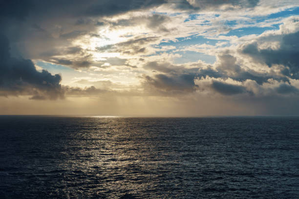 istock The sun shines above the ocean, piercing through fluffy clouds 2159367864
