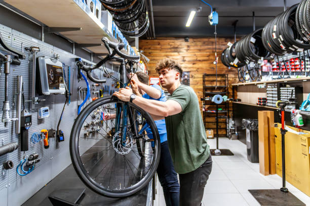man checking bicycle in workshop side view on man checking bicycle in bicycle workshop bike workshop stock pictures, royalty-free photos & images
