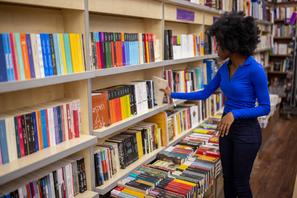Young Black woman browsing for a book to buy on bookshelves in a bookstore.