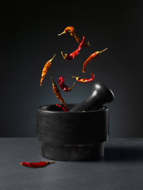 Chili peppers falling into mortar and pestle