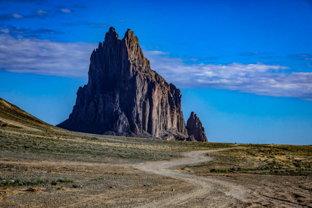 Ship Rock, New Mexico on a pleasant spring morning, dirt road through the desert leading to the famous landmark.