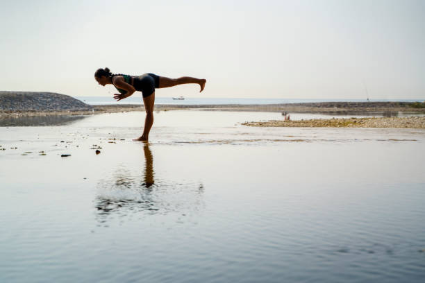 istock Woman practicing yoga on the beach at sunrise 2159382260