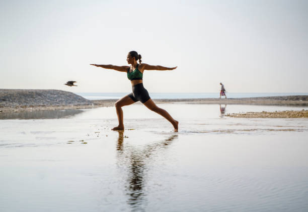 istock Woman practicing yoga on the beach at sunrise 2159382278