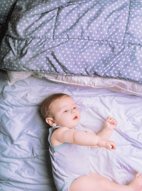 istock Adorable baby boy lying and playing on a bed 2159387229