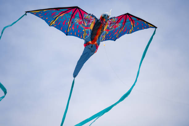 Dinosaur toy kite flying in the air with long ribbons on its tail and with menacing teeth
