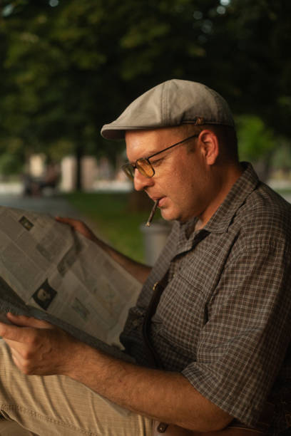 istock Man smoking a cigarette and reading newspapers in the park 2159390170