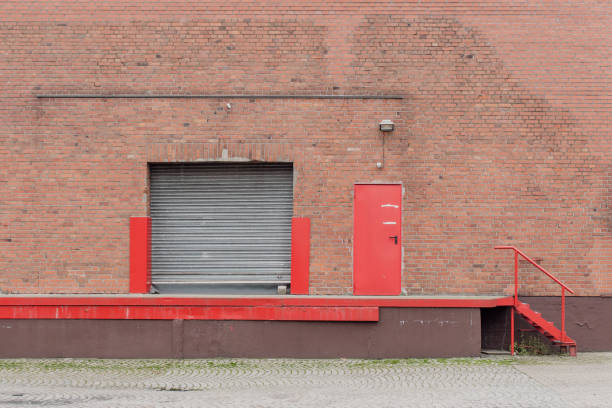 Red loading ramp in front of an old brick warehouse with closed roller door