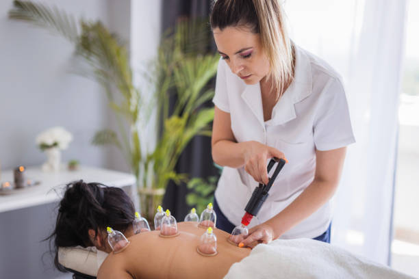 Therapist performing blood suction with cups Patient having a hajamat therapy performed at therapist's office cupping therapy stock pictures, royalty-free photos & images