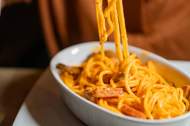 istock Person eating spaghetti with creamy orange sauce 2159398732