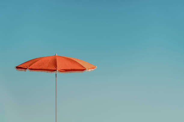 minimalistic isolated view of an orange parasol or blue sky