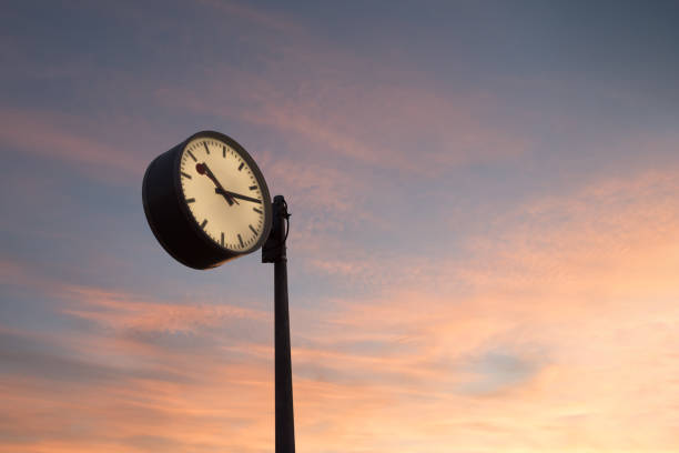 istock Close-up of a public clock against sunset sky 2159400820