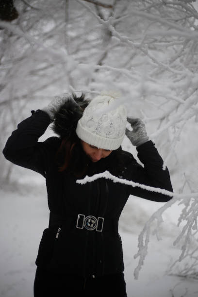 Smiling woman wearing scarf in a winter cold day. Happy girl in a sweater outdoor in snow. Beautiful smiling woman with hat and scarf outdoor looking away.