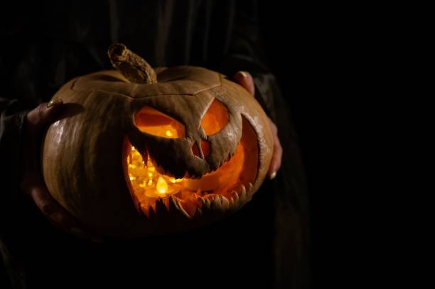 istock The witch is holding a pumpkin jack o lantern glowing in the dark. Halloween. 2159408039