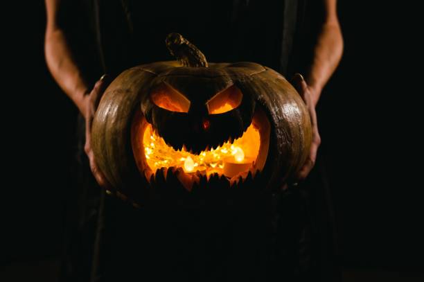 istock The witch is holding a pumpkin jack o lantern glowing in the dark. Halloween. 2159408245