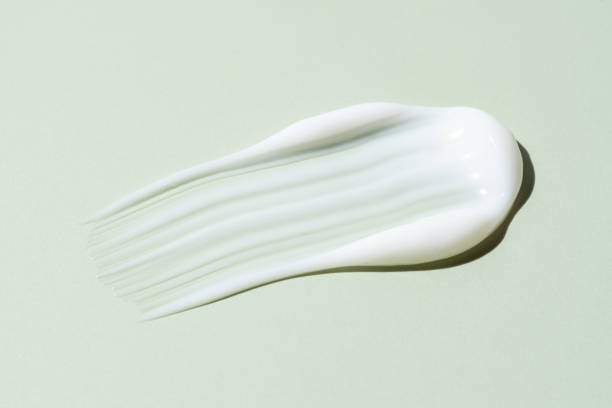 istock Cosmetic product smear white moisturizing lotion isolated on green, squeezed out and smeared portion of skincare cream product testing. 2159408417