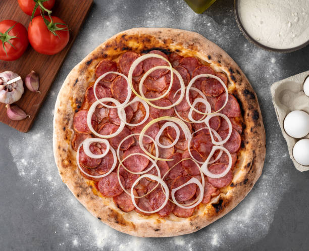 istock Calabrese sausage style pizza over stone background with ingredients 2159409059