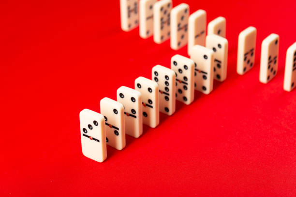 Domino effect ready to begin. Acrylic pieces in a row. Isolated on red background.