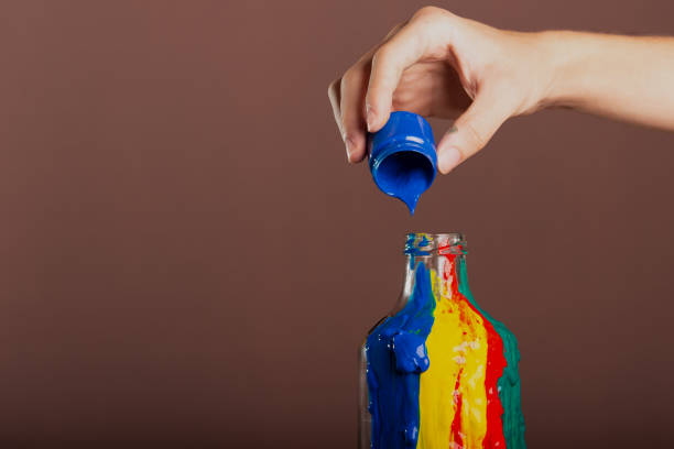 istock Painters hand pouring blue paint into a glass bottle. abstract art. 2159415764