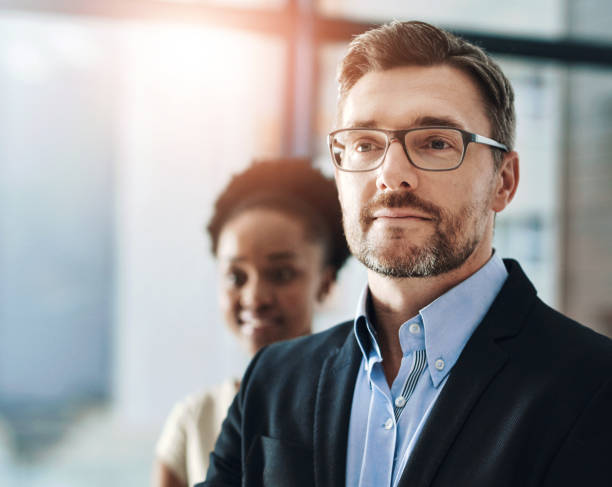 Office, future and vision with business man in corporate workplace for ambition or professional career. Glasses, planning or thinking with employee in suit at workplace for inspiration or opportunity