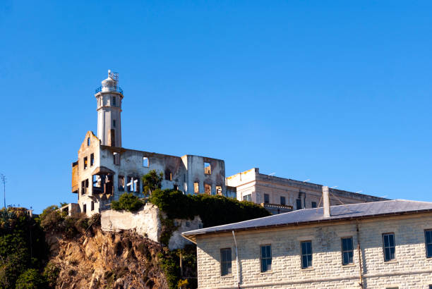 Alcatraz Island is situated in the middle of San Francisco Bay, California. The image captures the historic prison buildings which is perched on the rocky island, surrounded by the blue waters of the bay. The infamous Alcatraz Federal Penitentiary, with its imposing structure and watchtower, stands as a significant landmark against the backdrop of the distant city skyline. The island, now a popular tourist destination, is steeped in history and intrigue, offering a glimpse into its storied past as one of America's most notorious prisons.