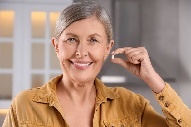 istock Menopause, hormone replacement therapy. Happy woman holding pill in kitchen 2159426871