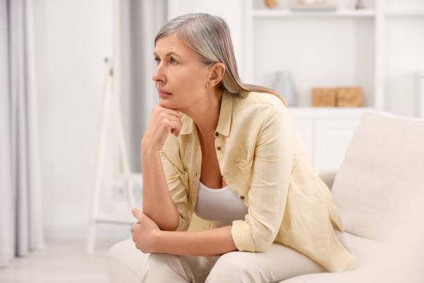 istock Menopause, mood changes. Sad woman on sofa at home, space for text 2159426909
