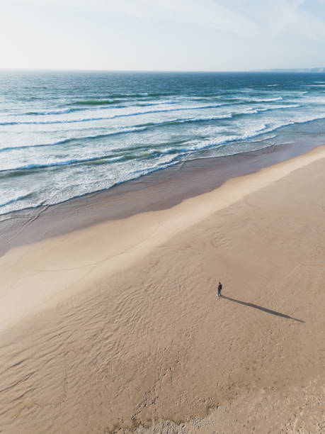 istock Lonely man standing on a wild beach watching the ocean 2159427978