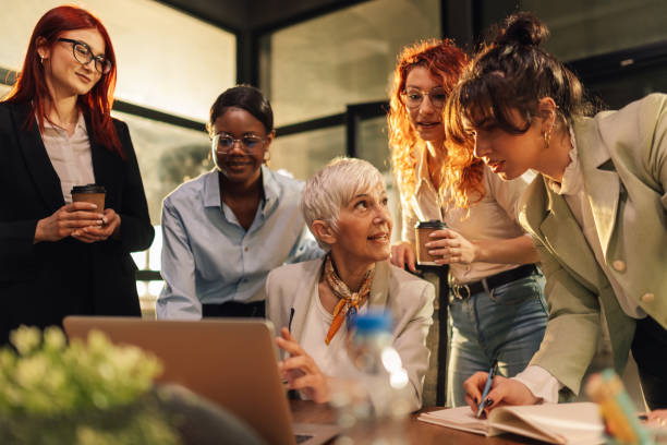 istock Senior female boss discussing project on laptop with interracial team. 2159431345