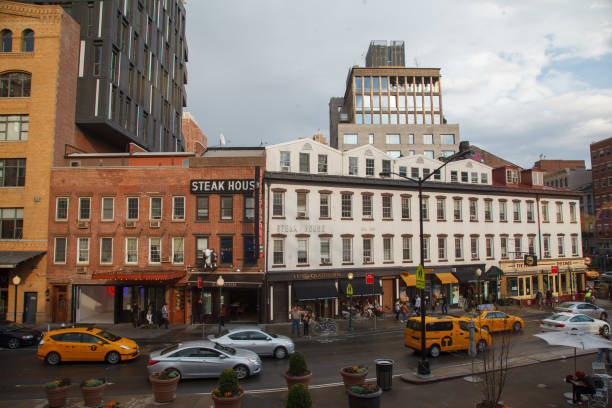 New York City, United States, 6 Sept 2023: Manhattan Midtown Irving street corner, crossroad intersection, Gramercy, USA. People pedestrians. Yellow taxi. Red brick house wall covered ivy plant leaves