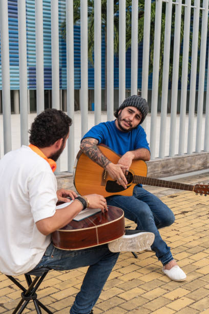 Two Musicians Engaging in an Outdoor Jam Session Two musicians with guitars discussing and playing music outdoors. acoustic guitar tattoos stock pictures, royalty-free photos & images