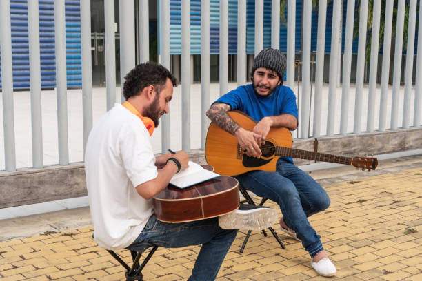 Two Musicians Practicing and Discussing Outdoors Two musicians with guitars practicing and discussing music outside. acoustic guitar tattoos stock pictures, royalty-free photos & images