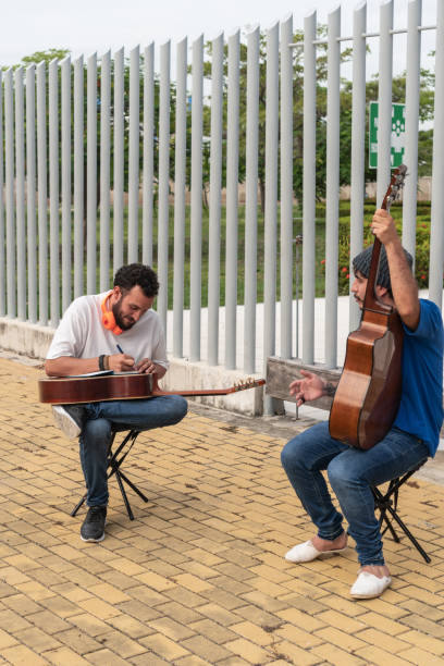 Two Musicians Engaged in Outdoor Guitar Practice Two musicians with guitars practicing and discussing music outdoors. acoustic guitar tattoos stock pictures, royalty-free photos & images