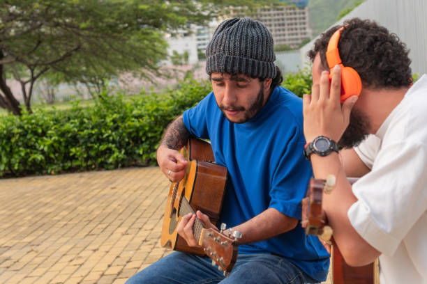 istock Latin men playing guitars and singing together outdoors on a sunny day. 2159441315