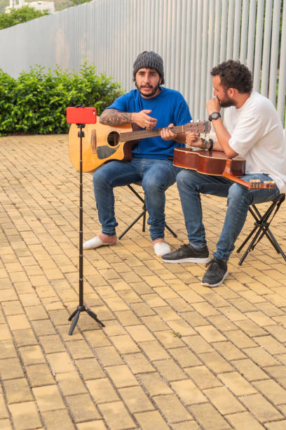 istock Two young men teaching guitar techniques, recording with a smartphone outdoors. 2159441328