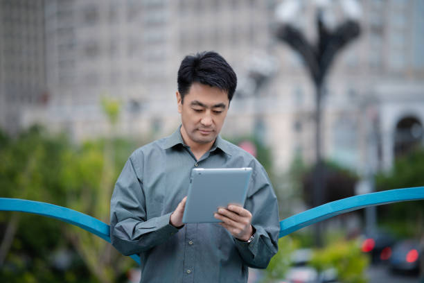 Middle-aged man using digital tablet in city street