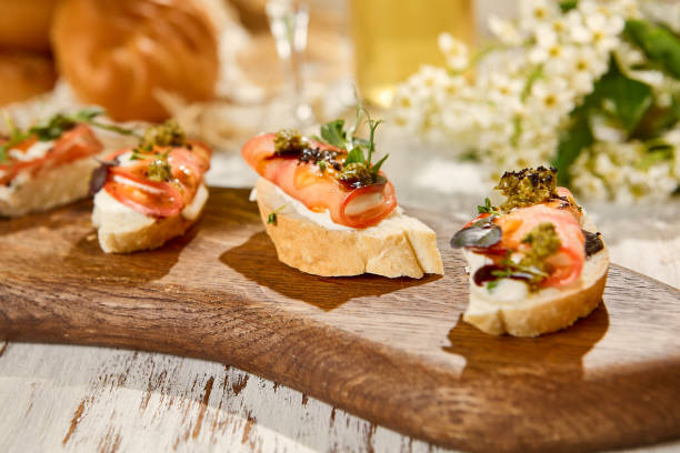 istock Assorted Tomato and Cheese Bruschetta on Wooden Platter under Sunlight 2159445763